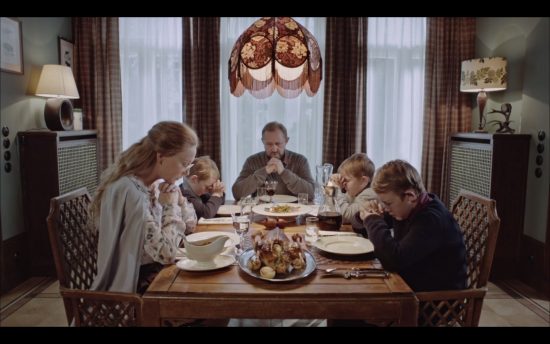 Cate Blanchett bendiciendo la mesa familiar con el manifiesto de Claes Oldenburg, en Manifest, Julian Rosefeldt, 2015